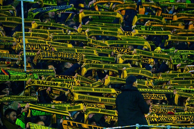 Fans show their scarves as a sign of respect following the death of a fan during the German first division Bundesliga football match Borussia Dortmund v 1 FSV Mainz 05 in Dortmund, on March 13, 2016. / AFP / Sascha SCHUERMANN / RESTRICTIONS: DURING MATCH TIME: DFL RULES TO LIMIT THE ONLINE USAGE TO 15 PICTURES PER MATCH AND FORBID IMAGE SEQUENCES TO SIMULATE VIDEO. == RESTRICTED TO EDITORIAL USE == FOR FURTHER QUERIES PLEASE CONTACT DFL DIRECTLY AT + 49 69 650050
        (Photo credit should read SASCHA SCHUERMANN/AFP/Getty Images)