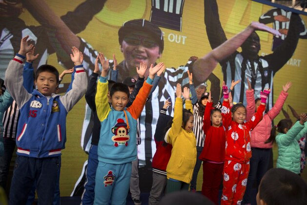 Chinese children dance along with a video demonstrating the various signals used by football referees at a National Football League publicity event held in Beijing, Sunday, Nov. 8, 2015. The NFL has been aggressively promoting football in China hoping to take advantage of rising income and growing taste for exotic foreign sports. (AP Photo/Mark Schiefelbein)