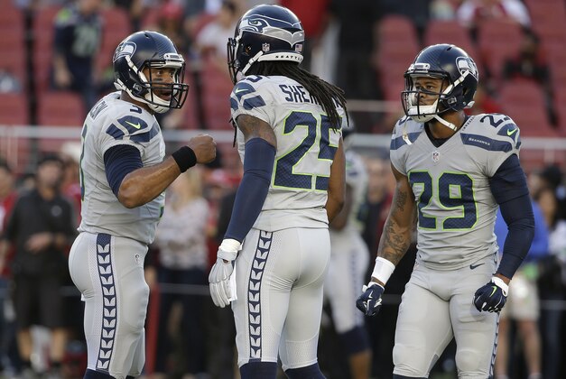 Seattle Seahawks quarterback Russell Wilson (3), cornerback Richard Sherman (25) and free safety Earl Thomas (29) warm up before an NFL football game against the San Francisco 49ers in Santa Clara, Calif., Thursday, Oct. 22, 2015. (AP Photo/Marcio Jose Sanchez)