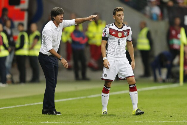 Germany's coach Joachim Loew, left, advises Mesut Oezil during the Euro 2016 qualifying match between Germany and Poland at the Commerzbank Arena in Frankfurt, Germany, Friday, Sept. 4, 2015. (AP Photo/Michael Probst)