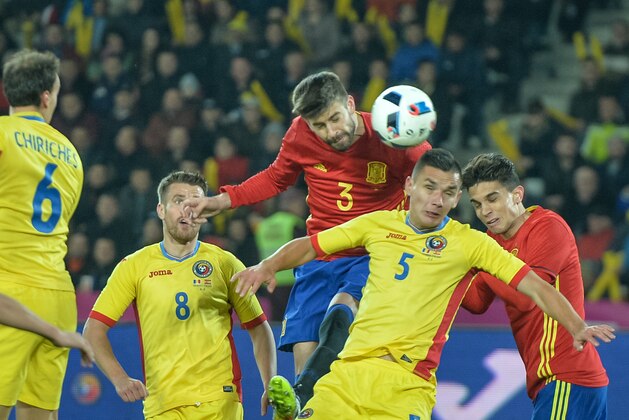 Spains defender Gerard Pique (C) and Romanias defender Ovidiu Stefan Hoban vie for the ball during the friendly football match between Romania and Spain in Cluj Napoca, Romania on March 27, 2016. / AFP / ANDREI PUNGOVSCHI        (Photo credit should read ANDREI PUNGOVSCHI/AFP/Getty Images)