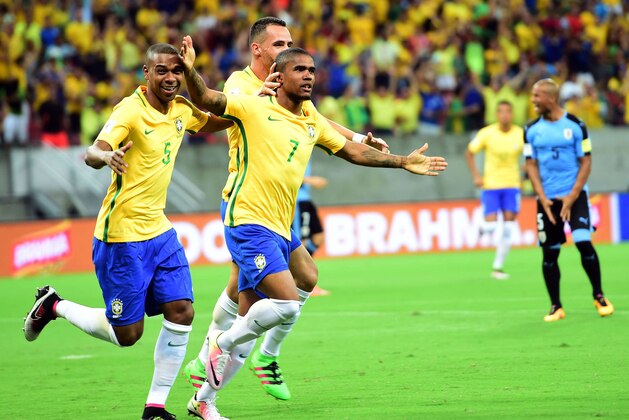 Brazil's Douglas Costa (R) celebrates after scoring against Uruguay during their Russia 2018 FIFA World Cup South American Qualifiers' football match, in Recife, northeastern Brazil, on March 25, 2016.   AFP PHOTO / CHRISTOPHE SIMON / AFP / CHRISTOPHE SIMON        (Photo credit should read CHRISTOPHE SIMON/AFP/Getty Images)