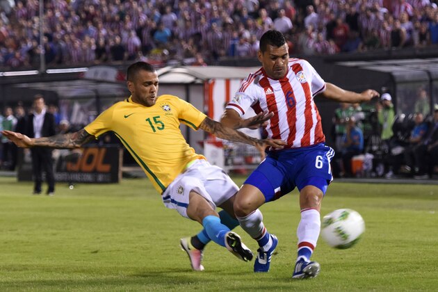 Brazil's Daniel Alves (L) and Paraguay's Miguel Samudio vie for the ball during their Russia 2018 FIFA World Cup South American Qualifiers' football match in Asuncion, on March 29, 2016.    AFP PHOTO / PABLO BURGOS / AFP / PABLO BURGOS        (Photo credit should read PABLO BURGOS/AFP/Getty Images)