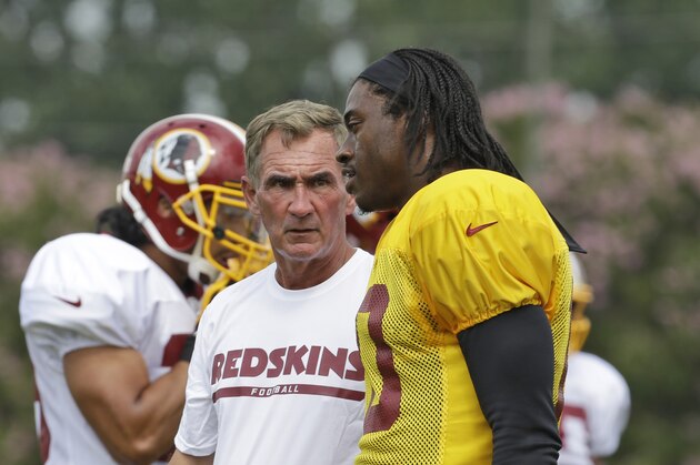 Washington Redskins quarterback Robert Griffin III, right, talks with head coach Mike Shanahan, during the NFL football teams training camp in Richmond, Va. Saturday, July 27, 2013.   (AP Photo/Steve Helber)