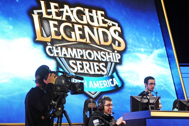 A cameraman lines up his shot of Team Curse Venezuelan player Diego 'Quas' Ruiz (C) before the start of a match against Cloud 9 during the League of Legends North American Championship Series Spring round robin competition, at the MBS Media Campus in Manhattan Beach, California February 22, 2014.  League of Legends, one of the world's most popular multiplayer online battle arena video game, has a fully professional competitive league and a top prize of one million dollars.   AFP PHOTO / ROBYN BECK        (Photo credit should read ROBYN BECK/AFP/Getty Images)