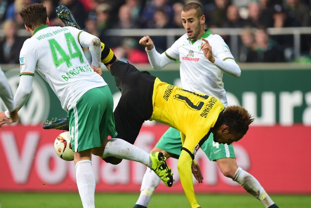 Dortmund's Gabonese striker Pierre-Emerick Aubameyang (C) takes a tumble past Bremen's midfielder Philipp Bargfrede (L) and Bremen's Spanish defender Alejandro Galvez (R) during the German first division Bundesliga football match Werder Bremen vs Borussia Dortmund in Bremen, northern Germany, on October 31, 2015.    
AFP PHOTO / JOHN MACDOUGALL
RESTRICTIONS: DURING MATCH TIME: DFL RULES TO LIMIT THE ONLINE USAGE TO 15 PICTURES PER MATCH AND FORBID THE IMAGE SEQUENCES TO SIMULATE VIDEO.
== RESTRICTED TO EDITORIAL USE == 
FOR FURTHER QUERIES PLEASE CONTACT DFL DIRECTLY AT + 49 69 650050        (Photo credit should read JOHN MACDOUGALL/AFP/Getty Images)