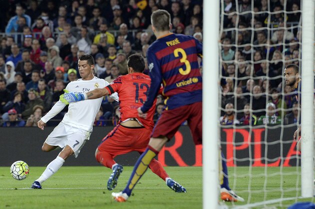 Real Madrid's Portuguese forward Cristiano Ronaldo (L) shoots next to Barcelona's Chilean goalkeeper Claudio Bravo to score a goal during the Spanish league 'Clasico' football match FC Barcelona vs Real Madrid CF at the Camp Nou stadium in Barcelona on April 2, 2016. / AFP / JOSEP LAGO        (Photo credit should read JOSEP LAGO/AFP/Getty Images)