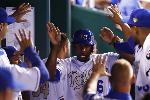 KANSAS CITY, MO - APRIL 03:  Lorenzo Cain #6 of the Kansas City Royals is congratulated by teammates in the dugout after scoring during the 6th inning of the opening day game against the New York Mets at Kauffman Stadium on April 3, 2016 in Kansas City, Missouri. (Photo by Jamie Squire/Getty Images)