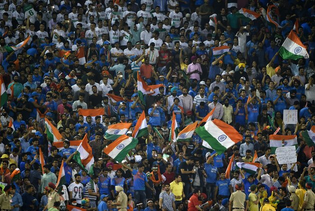 Indian supporters wave flags as they cheer ahead of the start of the World T20 cricket tournament match between India and Australia at The Punjab Cricket Stadium Association Stadium in Mohali on March 27, 2016. / AFP / MONEY SHARMA        (Photo credit should read MONEY SHARMA/AFP/Getty Images)