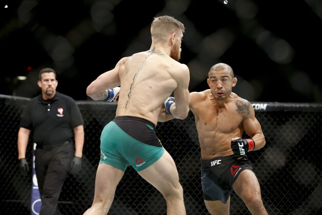 Conor McGregor, left, fights Jose Aldo during a featherweight  championship mixed martial arts bout at UFC 194, Saturday, Dec. 12, 2015, in Las Vegas. (AP Photo/John Locher)