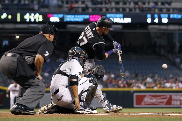 Colorado Rockies' Trevor Story (27) connects for a fly ball as Arizona Diamondbacks' Welington Castillo, middle, and umpire Brian O'Nora (7) watch during the first inning of a baseball game Tuesday, April 5, 2016, in Phoenix.  The Diamondbacks defeated the Rockies 11-6. (AP Photo/Ross D. Franklin)