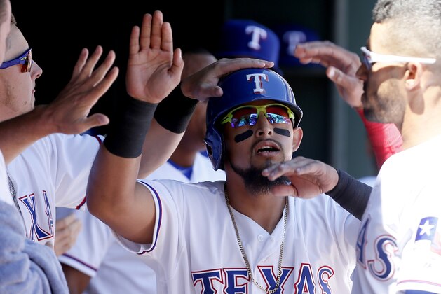 Texas Rangers' Rougned Odor, center, is congratulated by teammates after scoring a run on a RBI double hit by Justin Ruggiano, not pictured, during the second inning of a baseball game against the Seattle Mariners Wednesday, April 6, 2016, in Arlington, Texas. (AP Photo/Brandon Wade)