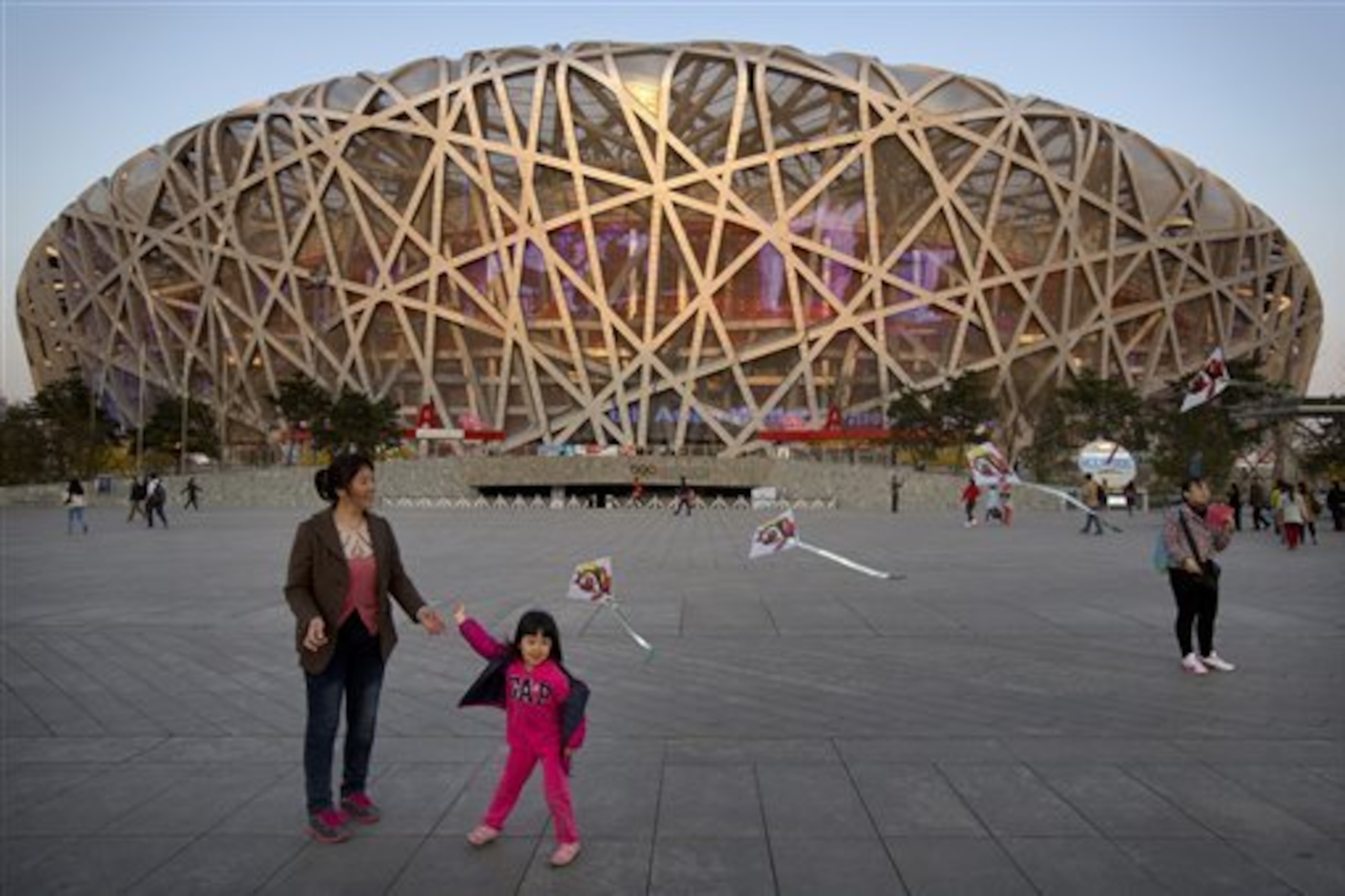 FILE - In this March 28, 2015 file photo, of a girl as she flies a kite on Olympic Green near Beijing National Stadium, also known as the Birds Nest.  The IAAF said Tuesday Aug. 11, 2015 that 28 athletes tested positive after their doping samples from the 2005 and 2007 world championships were reanalyzed. Track and field's governing body did not name any of the athletes, who produced 32 positive findings in tests from the 2005 championships in Helsinki and 2007 meeting in Osaka. The next athletics world championships will begin in Beijing on Aug. 22 . (AP Photo/Mark Schiefelbein, File)