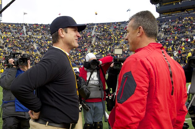 Michigan head coach Jim Harbaugh, left, talks with Ohio State head coach Urban Meyer, right, on the Michigan Stadium field before an NCAA college football game in Ann Arbor, Mich., Saturday, Nov. 28, 2015. (AP Photo/Tony Ding)