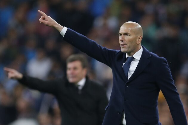 Real Madrid's headcoach Zinedine Zidane, right, and Wolfsburg's headcoach Dieter Hecking, rear, both point as they coach their players during the Champions League 2nd leg quarterfinal soccer match between Real Madrid and VfL Wolfsburg at the Santiago Bernabeu stadium in Madrid, Spain, Tuesday April 12, 2016. (AP Photo/Paul White)