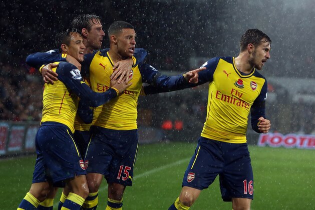 Arsenal's Chilean striker Alexis Sanchez (L) celebrates with team-mates Arsenal's Welsh midfielder Aaron Ramsey (R) and Arsenal's English midfielder Alex Oxlade-Chamberlain (C) after scoring the opening goal during the English Premier League football match between Swansea City and Arsenal at The Liberty Stadium in Swansea, south Wales on November 9, 2014. AFP PHOTO / GEOFF CADDICK

RESTRICTED TO EDITORIAL USE. No use with unauthorized audio, video, data, fixture lists, club/league logos or live services. Online in-match use limited to 45 images, no video emulation. No use in betting, games or single club/league/player publications.        (Photo credit should read GEOFF CADDICK/AFP/Getty Images)