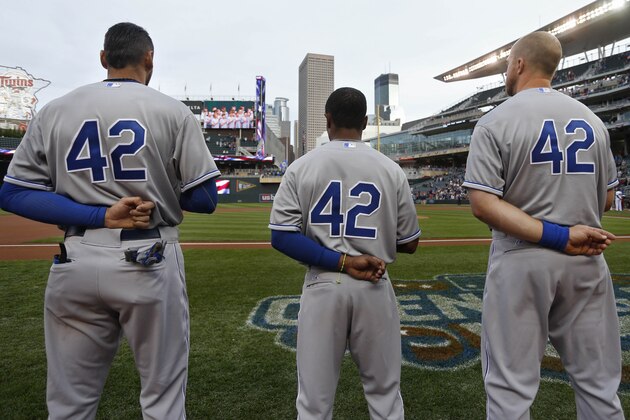 Kansas City Royals Paulo Orlando, Terrance Gore, and Erik Kratz, left to right, stand for the national anthem prior to the game with the Minnesota Twins of a baseball game Wednesday, April 15, 2015, in Minneapolis. Players were wearing  number 42 today to honor the anniversary of the first game Jackie Robinson  played for the Brooklyn Dodgers. The Twins won 3-1. (AP Photo/Bruce Kluckhohn)