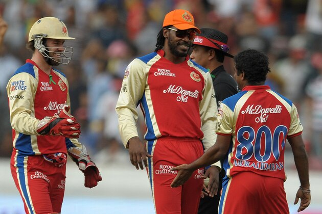 Royal Challengers Bangalore bowler Muttiah Muralitharan (R) celebrates with teammates Chris Gayle (C) and AB De Villers (L) after taking the wicket of unseen Deccan Chargers captain Kumar Sangakkara during the IPL Twenty20 cricket match between Deccan Chargers and Royal Challengers Bangalore at Rajiv Gandhi International Stadium in Hyderabad on May 20, 2012.   RESTRICTED TO EDITORIAL USE. MOBILE USE WITHIN NEWS PACKAGE. AFP PHOTO/Noah SEELAM        (Photo credit should read NOAH SEELAM/AFP/GettyImages)