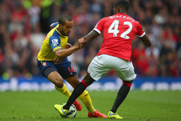 MANCHESTER, ENGLAND - MAY 17:  Theo Walcott of Arsenal takes on Tyler Blackett of Manchester United during the Barclays Premier League match between Manchester United and Arsenal at Old Trafford on May 17, 2015 in Manchester, England.  (Photo by Clive Rose/Getty Images)