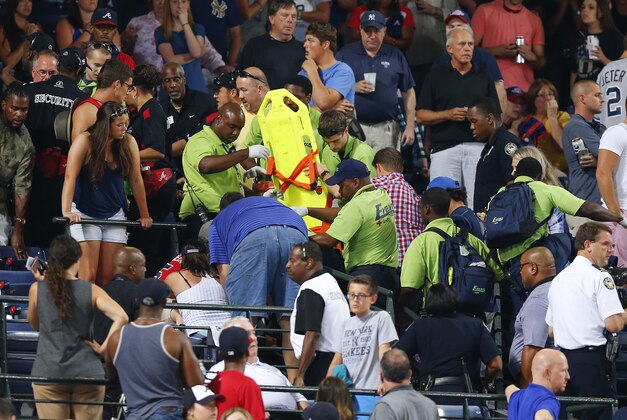Fans look on as emergency medical personnel work on a fan who fell from an upper deck at Turner Field during a baseball game between New York Yankees and Atlanta BravesSaturday, Aug. 29, 2015, in Atlanta. (AP Photo/John Bazemore)