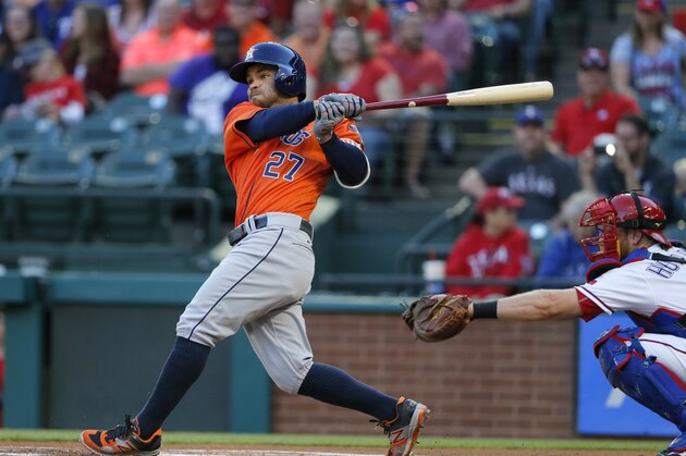Houston Astros' Jose Altuve follows through on a double to left as Texas Rangers' Bryan Holaday watches during the first inning of a baseball game, Thursday, April 21, 2016, in Arlington, Texas. (AP Photo/Tony Gutierrez)