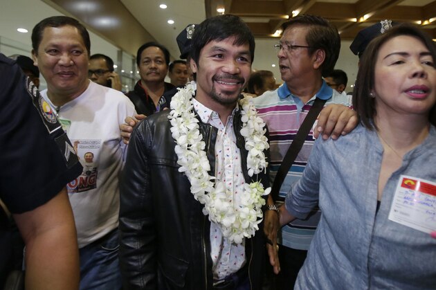 Filipino boxer and Congressman Manny Pacquiao, center, smiles as he arrives at the Ninoy Aquino International Airport in suburban Pasay city, south of Manila, Philippines, Thursday, April 14, 2016. Pacquiao beat American Timothy Bradley during their WBO welterweight title boxing match in Las Vegas. He is running for the senate in the elections next month. (AP Photo/Aaron Favila)