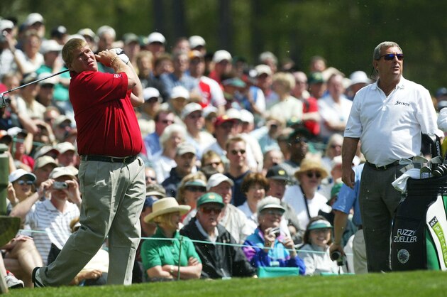 AUGUSTA, GA - APRIL 6:  John Daly of the USA hits a shot on the 12th tee as Fuzzy Zoeller looks on during the second practice day for the Masters at the Augusta National Golf Club on April 6, 2004 in Augusta, Georgia.  (Photo by David Cannon/Getty Images)