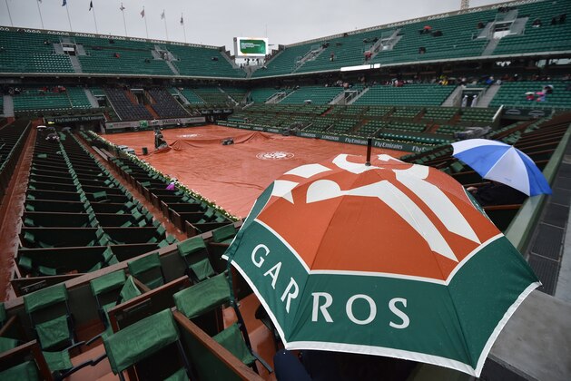 Spectators hold umbrellas as the match opposing France's Alize Cornet to Ukraine's Elina Svitolina is interrupted by rain during the women's fourth round at the Roland Garros 2015 French Tennis Open in Paris on May 31, 2015.   AFP PHOTO / PASCAL GUYOT        (Photo credit should read PASCAL GUYOT/AFP/Getty Images)