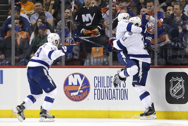 Tampa Bay Lightning right wing Ryan Callahan, center, jumps into the arms of center Brian Boyle (11) as Tampa Bay Lightning center Cedric Paquette (13) rushes in after Boyle scored the game-winning goal against the New York Islanders during the overtime period of Game 3 of the NHL hockey Stanley Cup Eastern Conference semifinals, Tuesday, May 3, 2016, in New York. The Lightning won 5-4. (AP Photo/Frank Franklin II)