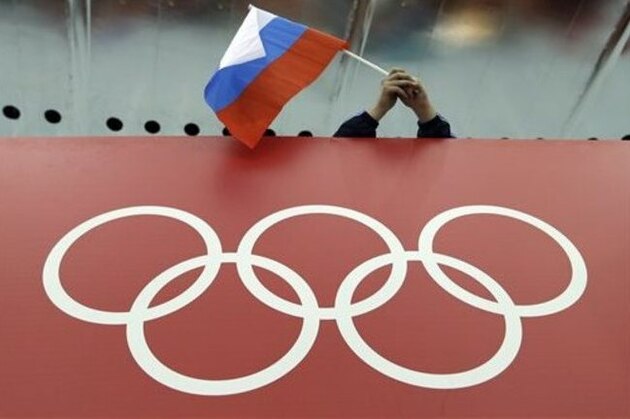 A Russian skating fan holds the country's national flag over the Olympic rings before the start of the men's 10,000-meter speedskating race at Adler Arena Skating Center during the 2014 Winter Olympics in Sochi, Russia, Tuesday, Feb. 18, 2014.(AP Photo/David J. Phillip )