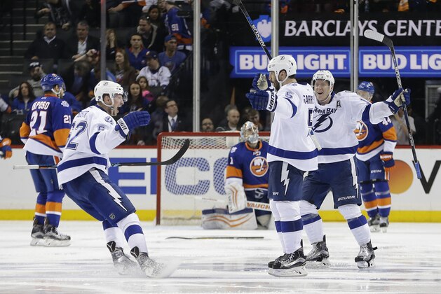Tampa Bay Lightning defenseman Andrej Sustr (62) and left wing Ondrej Palat (18) celebrate with defenseman Jason Garrison (5) after Garrison scored the winning goal against the New York Islanders during the overtime period of Game 4 of the NHL hockey Stanley Cup Eastern Conference semifinals, Friday, May 6, 2016, in New York. The Lightning won 2-1. (AP Photo/Frank Franklin II)