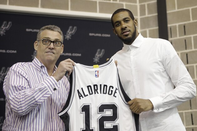 LaMarcus Aldridge, right, poses with San Antonio Spurs general manager R.C. Buford, left, and his new jersey during a news conference at the team's practice facility as he is formally introduced after he signed with the San Antonio Spurs NBA basketball team, Friday, July 10, 2015, in San Antonio. (AP Photo/Eric Gay)