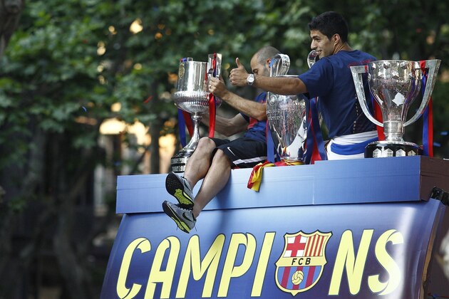 Barcelona's Uruguayan forward Luis Suarez (R) and  Barcelona's Argentinian defender Javier Mascherano pose with the three trophies on a bus parading through the streets of Barcelona as the team celebrate its victory over Juventus one day after the UEFA Champions League final football on June 7, 2015. Luis Suarez and Neymar scored second-half goals to give Barcelona a 3-1 Champions League final victory over Juventus on June 6, 2015 as the Spaniards became the first team to twice win the European treble.   AFP PHOTO/ QUIQUE GARCIA        (Photo credit should read QUIQUE GARCIA/AFP/Getty Images)