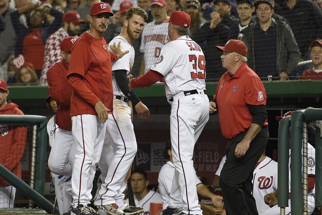 Washington Nationals' Bryce Harper, center, is restrained by pitching coach Mike Maddux, left, and hitting coach Rick Schu (39) after Harper was ejected in the dugout during the ninth inning of an interleague baseball game against the Detroit Tigers, Monday, May 9, 2016, in Washington. The Nationals won 5-4. (AP Photo/Nick Wass)
