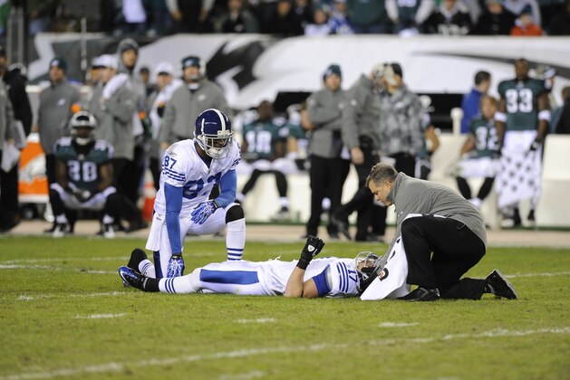 Indianapolis Colts wide receiver Austin Collie, center, lies on the field after being injured as teammate Reggie Wayne, left, and a trainer look on in the first half of an NFL football game against the Philadelphia Eagles, Sunday, Nov. 7, 2010 in Philadelphia. (AP Photo/Miles Kennedy)