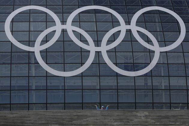A volunteer poses for a photograph beneath the Olympic rings at Olympic Park ahead of the 2014 Winter Olympics, Sunday, Feb. 2, 2014, in Sochi, Russia.(AP Photo/Felipe Dana)