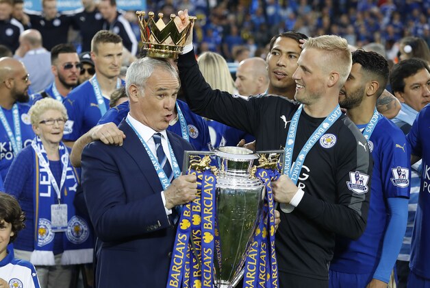 Leicester’s team manager Claudio Ranieri gets a crown by Leicester’s goalkeeper Kasper Schmeichel  as they lift the trophy as Leicester City celebrate becoming the English Premier League soccer champions at King Power stadium in Leicester, England, Saturday, May 7, 2016.(AP Photo/Matt Dunham)