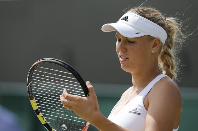 Denmark's Caroline Wozniacki checks her racquet after a point against Spain's Garbine Muguruza during their women's singles fourth round match on day seven of the 2015 Wimbledon Championships at The All England Tennis Club in Wimbledon, southwest London, on July 6, 2015.  Muguruza won 6-4, 6-4.  RESTRICTED TO EDITORIAL USE  --   AFP PHOTO / ADRIAN DENNIS        (Photo credit should read ADRIAN DENNIS/AFP/Getty Images)