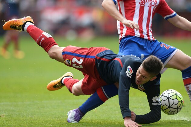 Atletico Madrid's Argentinian forward Luciano Vietto (L) falls next to Sporting Gijon's defender Jorge Mere during the Spanish league football match Real Sporting de Gijon vs Club Atletico de Madrid at El Molinon stadium in Gijon on March 19, 2016. / AFP / MIGUEL RIOPA        (Photo credit should read MIGUEL RIOPA/AFP/Getty Images)