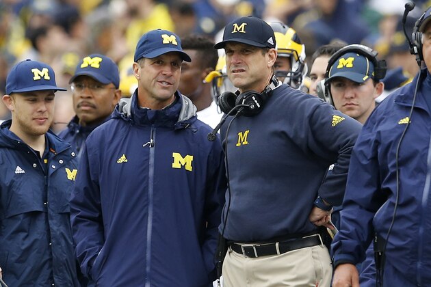 Baltimore Ravens head coach John Harbaugh, second from left, speaks with his brother, Michigan head coach Jim Harbaugh, on the sideline in the second half of an NCAA college football game against Maryland, Saturday, Oct. 3, 2015, in College Park, Md. (AP Photo/Patrick Semansky)