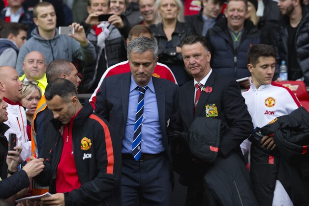 Chelsea's manager Jose Mourinho, center left, makes his way from the opposition dugout after greeting Manchester United manager Louis van Gaal, centre right, during their English Premier League soccer match between Manchester United and Chelsea at Old Trafford Stadium, Manchester, England, Sunday Oct. 26, 2014. (AP Photo/Jon Super)