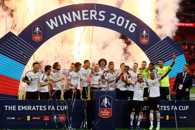 United’s manager Louis van Gaal, right, watches as the players pose with the trophy after they won the English FA Cup final soccer match between Manchester United and Crystal Palace at Wembley stadium in London, Saturday, May 21, 2016. United won 2-1. (AP Photo/Kirsty Wigglesworth)