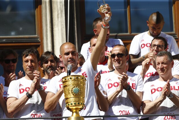 Bayern head coach Pep Guardiola celebrates behind the German soccer cup trophy on the balcony of the town hall at Marienplatz square in Munich, Germany, Sunday, May 22, 2016. (AP Photo/Matthias Schrader)