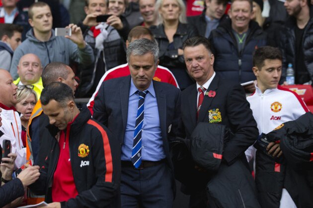 Chelsea's manager Jose Mourinho, center left, makes his way from the opposition dugout after greeting Manchester United manager Louis van Gaal, centre right, during their English Premier League soccer match between Manchester United and Chelsea at Old Trafford Stadium, Manchester, England, Sunday Oct. 26, 2014. (AP Photo/Jon Super)