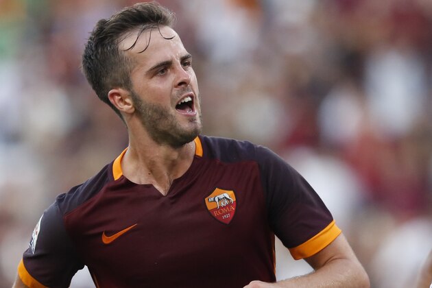 Roma’s Miralem Pjanic, left, celebrates  past Juventus’ Patrice Evra after scoring on a free kick during a Serie A soccer match between Roma and Juventus, at Rome's Olympic stadium, Sunday, Aug. 30, 2015. (AP Photo/Riccardo De Luca)