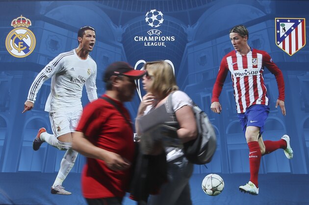 People walk by a billboard portraying Real Madrid's Cristiano Ronald, left, and Athletico Madrid's Fernando Torres, at the Champions Festival event area, in Milan, Italy, Thursday, May 26, 2016. The Champions League soccer final between Real Madrid and Atletico Madrid will be held at the San Siro stadium on Saturday, May 28, 2016. (AP Photo/Luca Bruno)