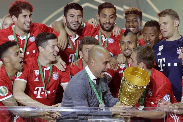 Bayern head coach Pep Guardiola holds up the trophy after winning the German soccer cup final match between Borussia Dortmund and FC Bayern Munich in Berlin, Germany, Saturday, May 21, 2016. (AP Photo/Markus Schreiber)
