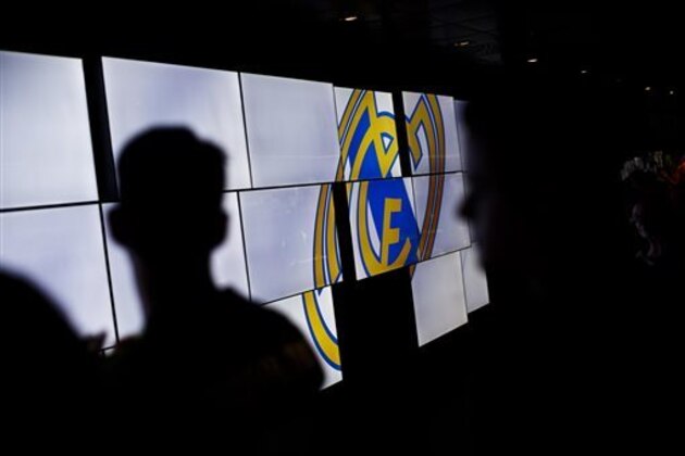 In this picture taken on May 18, 2014, Real Madrid's supporters are backlighted by screens displaying the Real Madrid team emblem on the trophies gallery of the Santiago Bernabeu stadium in Madrid, Spain. The European Union is investigating whether government loan guarantees for seven soccer clubs violate EU competition law, designed in part to prevent businesses from enjoying unfair advantage through state intervention. The probe is examining tax breaks granted to the Real Madrid, Barcelona, Athletic Bilbao and Osasuna soccer clubs _ but that’s a small part of government assistance to Spain’s soccer league, according to the AP review.  (AP Photo/Daniel Ochoa de Olza)