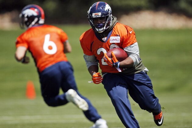 Denver Broncos running back C.J. Anderson, front, runs with the ball after taking a handoff from quarterback Mark Sanchez during NFL football practice Tuesday, May 24, 2016, at the team's headquarters in Englewood, Colo. (AP Photo/David Zalubowski)