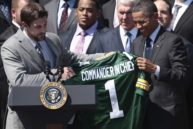 President Barack Obama is presented with a Green Bays Packers football jersey by quarterback Aaron Rodgers, left, during a ceremony honoring the Super Bowl XLV Champion Green Bay Packers, Friday, Aug. 12, 2011, on the South Lawn of the White House in Washington. At center is General Manager Ted Thompson. (AP Photo/Pablo Martinez Monsivais)